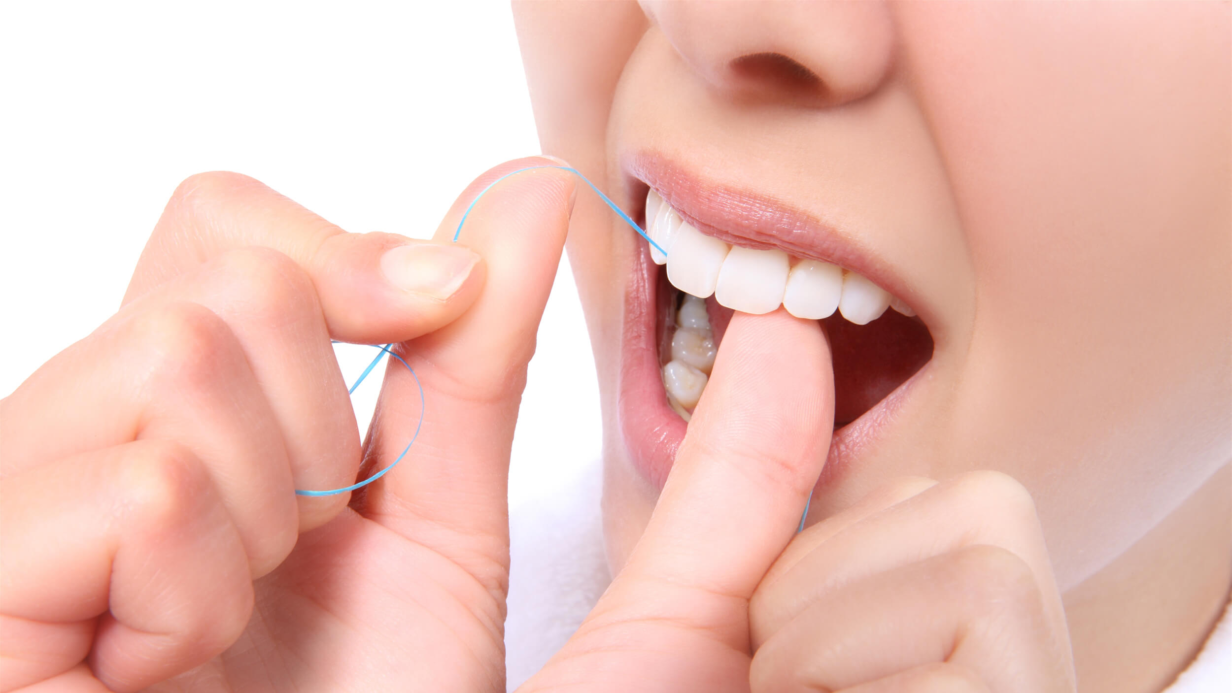 A close-up of a woman flossing her teeth