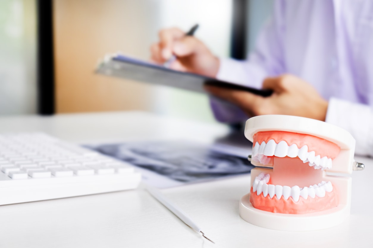 dentist with tooth model in dental office or clinic