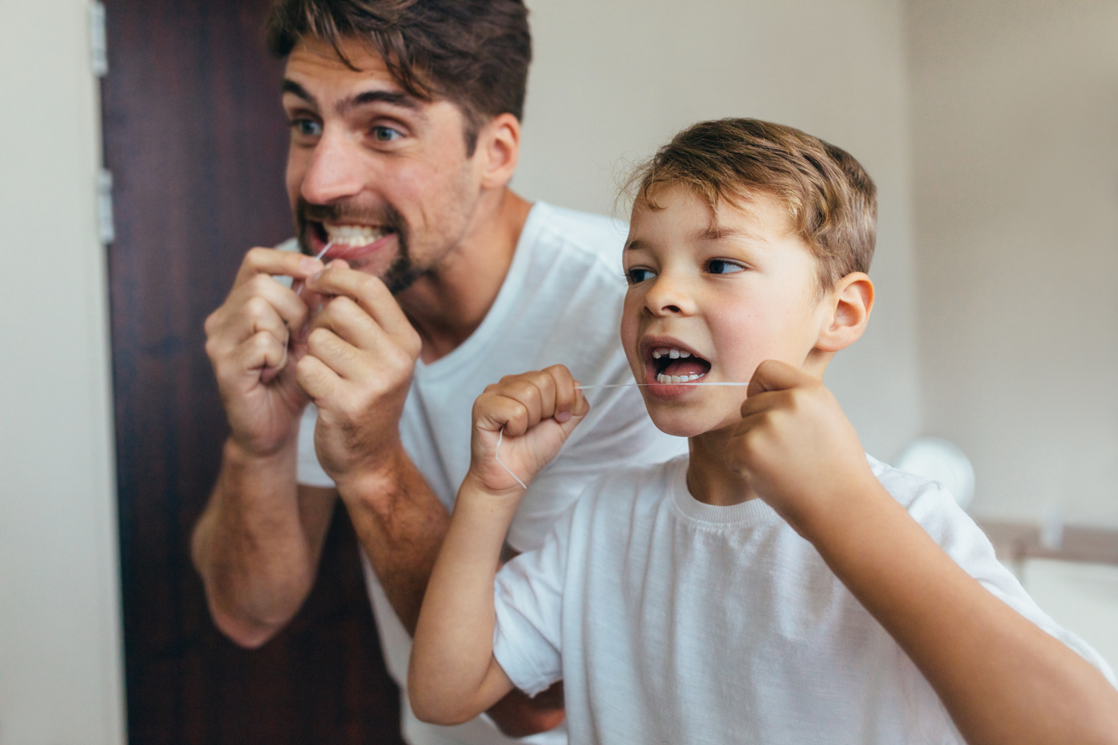 Father and son flossing, side angle