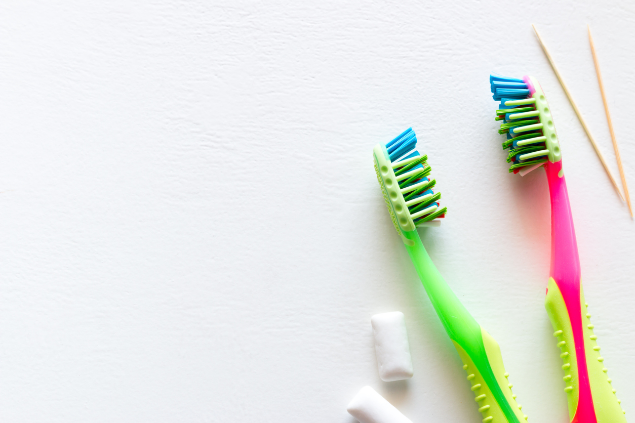 colored toothbrushes, toothpicks, and tic-tacs on white background